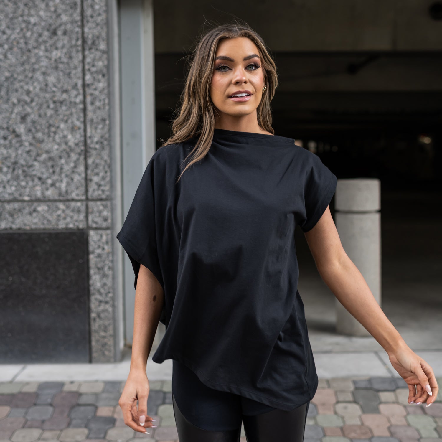A woman wearing a black asymmetrical organic cotton t-shirt by Malaika New York