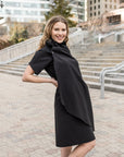 A woman wearing a knee length black shift dress by Malaika New York