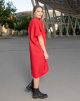 A woman wearing a pleated red shift dress by Malaika New york