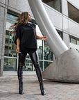 A woman wearing a pair of faux leather leggings & an asymmetrical tee