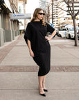 A woman wearing sun glasses and a long black shift dress by Malaika New York