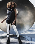Dark skinned woman with sun glasses wearing light weight summer linen vest with a high neck paired with silver leggings and dr. martins boots. Look by Malaika New York