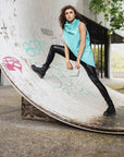 A woman wearing a mint green vest & a pair of black faux leather leggings