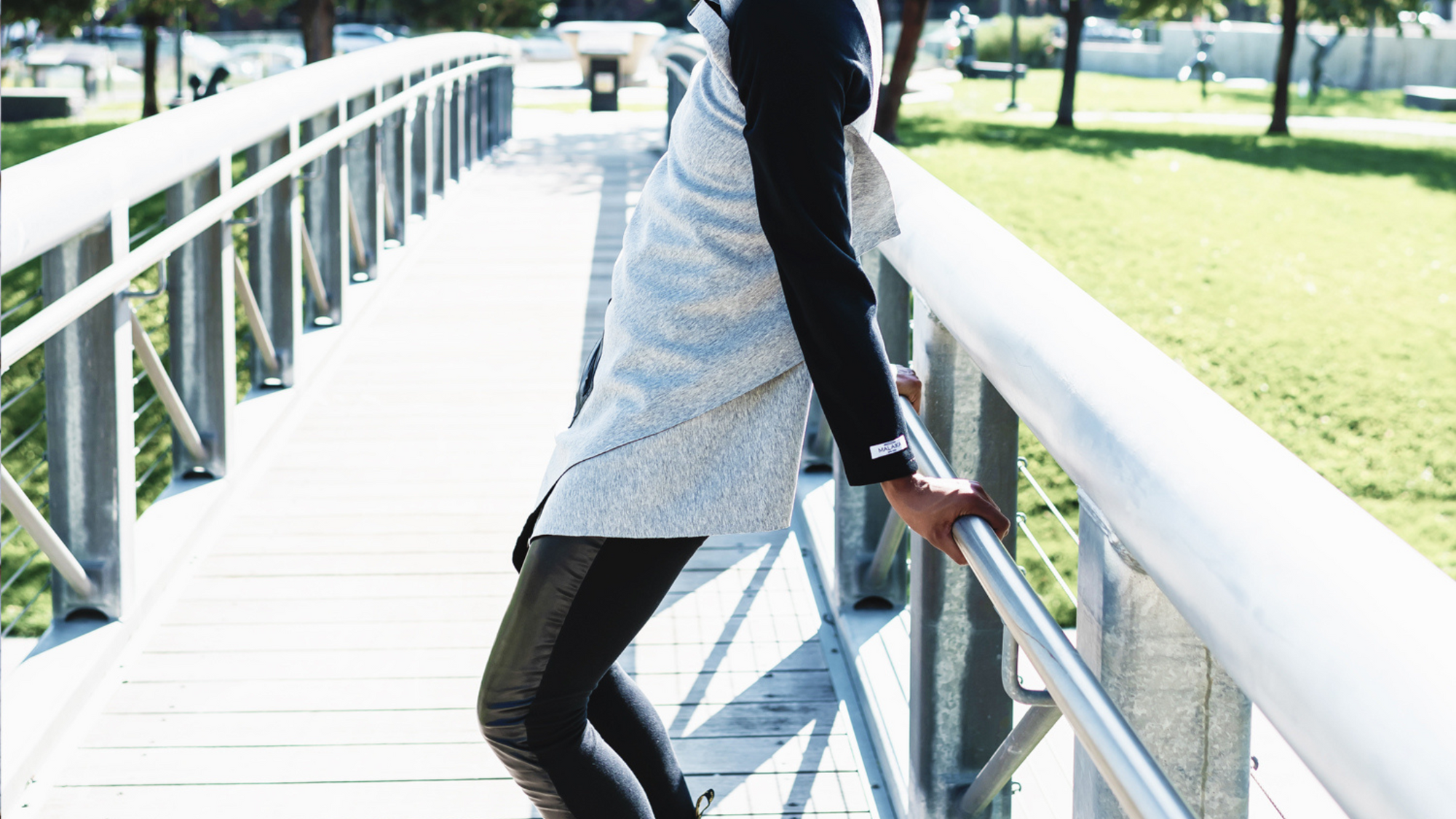 A woman standing on a bridge wrapped into a beautiful grey organic cotton cardigan by Malaika New York