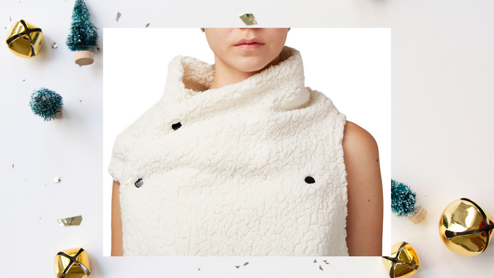 A woman wearing a fake fur vest in white with black snaps by Malaika New York