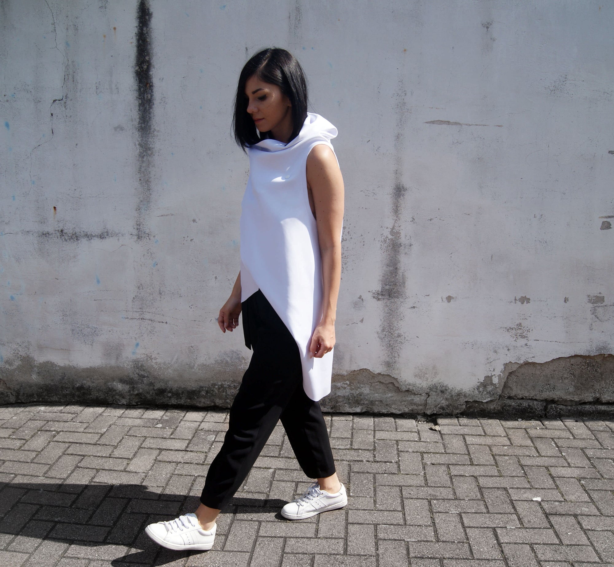 Minimalistc outfit with black pants and asymmetrical white vest by Malaika New York
