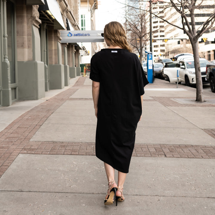 A Woman wearing a long black asymmetrical shift dress in organic cotton by Malaika New York