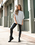 A woman wearing a grey oversized t-shirt and a pair of faux leather leggings by malaika New York