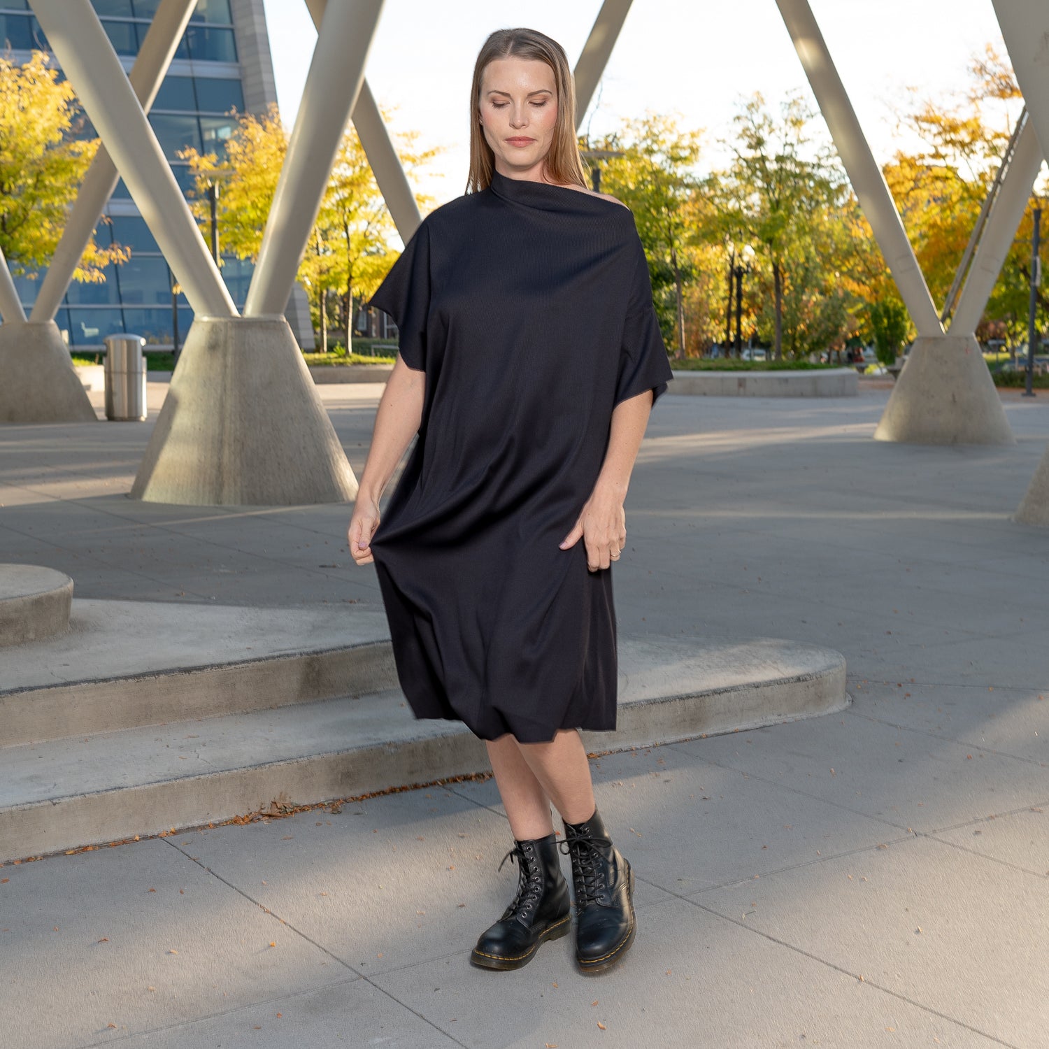 A woman wearing a pleated black off-the-shoulder shift dress by Malaika New York