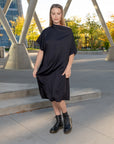A woman wearing a pleated black off-the-shoulder shift dress by Malaika New York