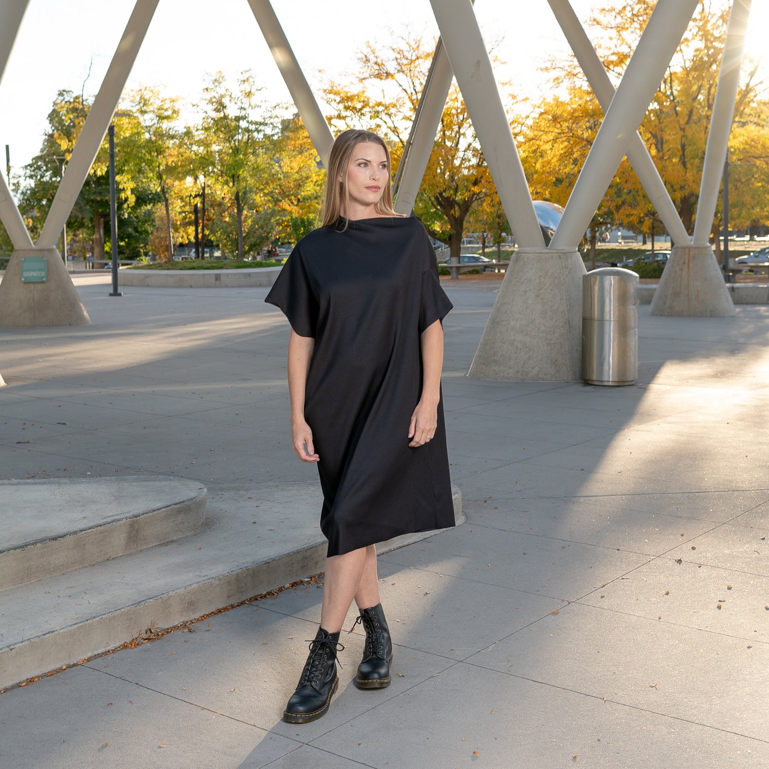 A front view of a woman wearing a pleated black shift dress by Malaika New York