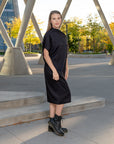 A woman wearing a pleated black shift dress by Malaika New York