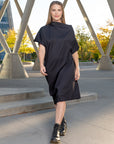 A woman wearing a black pleated shift dress by Malaika New York