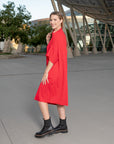 A woman wearing a red off-the-shoulder red shift dress by Malaika New York