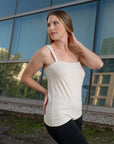 Side view of a woman wearing an off white sleeveless silk top 