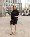 a woman wearing a black knee length shift dress by malaika new york
