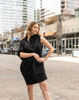 a woman wearing a versatile black knee length dress by malaika new york