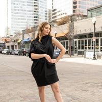a woman wearing a versatile black knee length dress by malaika new york