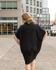 a woman walking away from the camera wearing a black shift dress by malaika new york