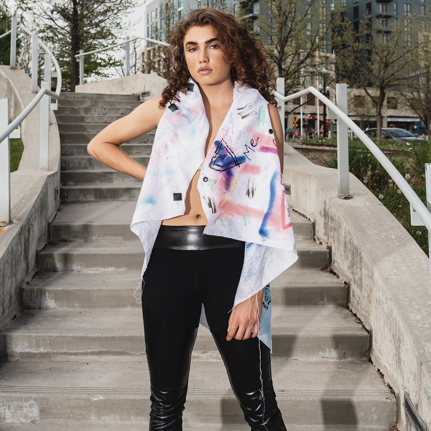 A woman wearing an asymmetrical linen hand painted vest open by Malaika New York x Tato