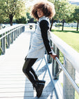 A woman wearing wearing a grey cardigan with black sleeves and a pair of faux leather leggings by Malaika New York