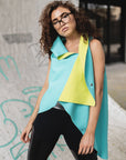 A woman wearing a mint green asymmetrical vest with a pair of black leggings