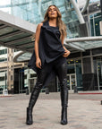 A woman wearing a black look by Malaika New York. Vegan leather leggings & an asymmetrical vest with old bike tube details.