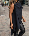 A side view of a woman wearing a beautiful asymmetrical vest by and vegan leather leggings by Malaika New York
