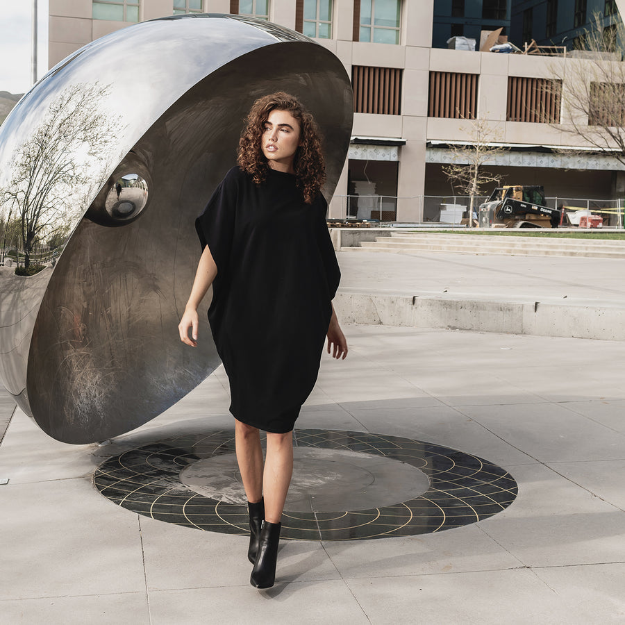 This is a photo of a women in our black hexagon t-shirt dress made from organic cotton. This shift dress is great for all body shapes.