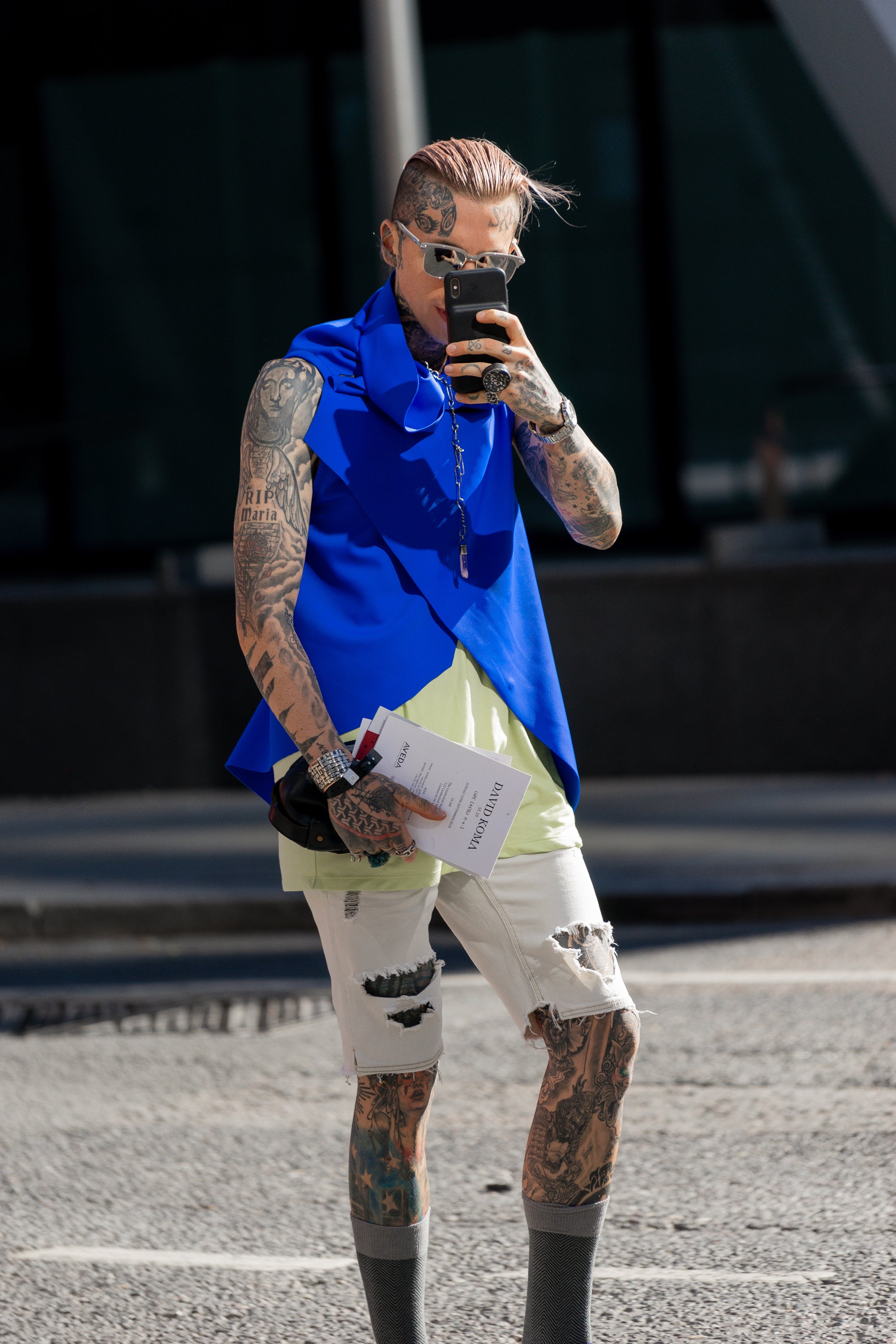 A guy wearing a blue asymmetrical vest with black snaps in ECONYL fabrics by Malaika New York