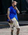 A guy wearing a blue asymmetrical vest with black snaps in ECONYL fabrics by Malaika New York