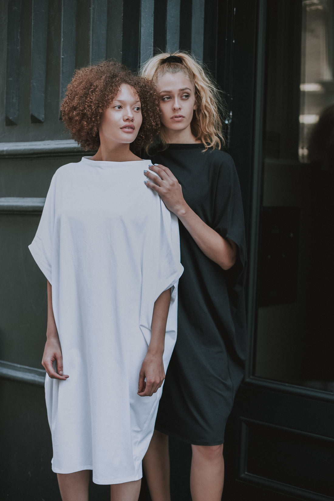 Two models wearing our midi white and black organic cotton dresses. Perfect to be used as a graduation dress. Made by Malaika New York