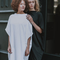 Two models wearing our midi white and black organic cotton dresses. Perfect to be used as a graduation dress. Made by Malaika New York