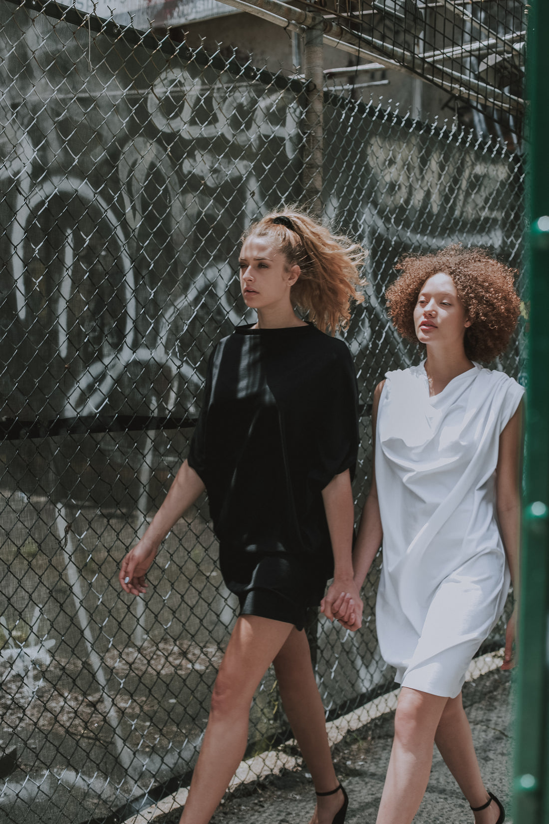 Two Models walking wearing our white & black shift dress in organic cotton. Made by Malaika New York