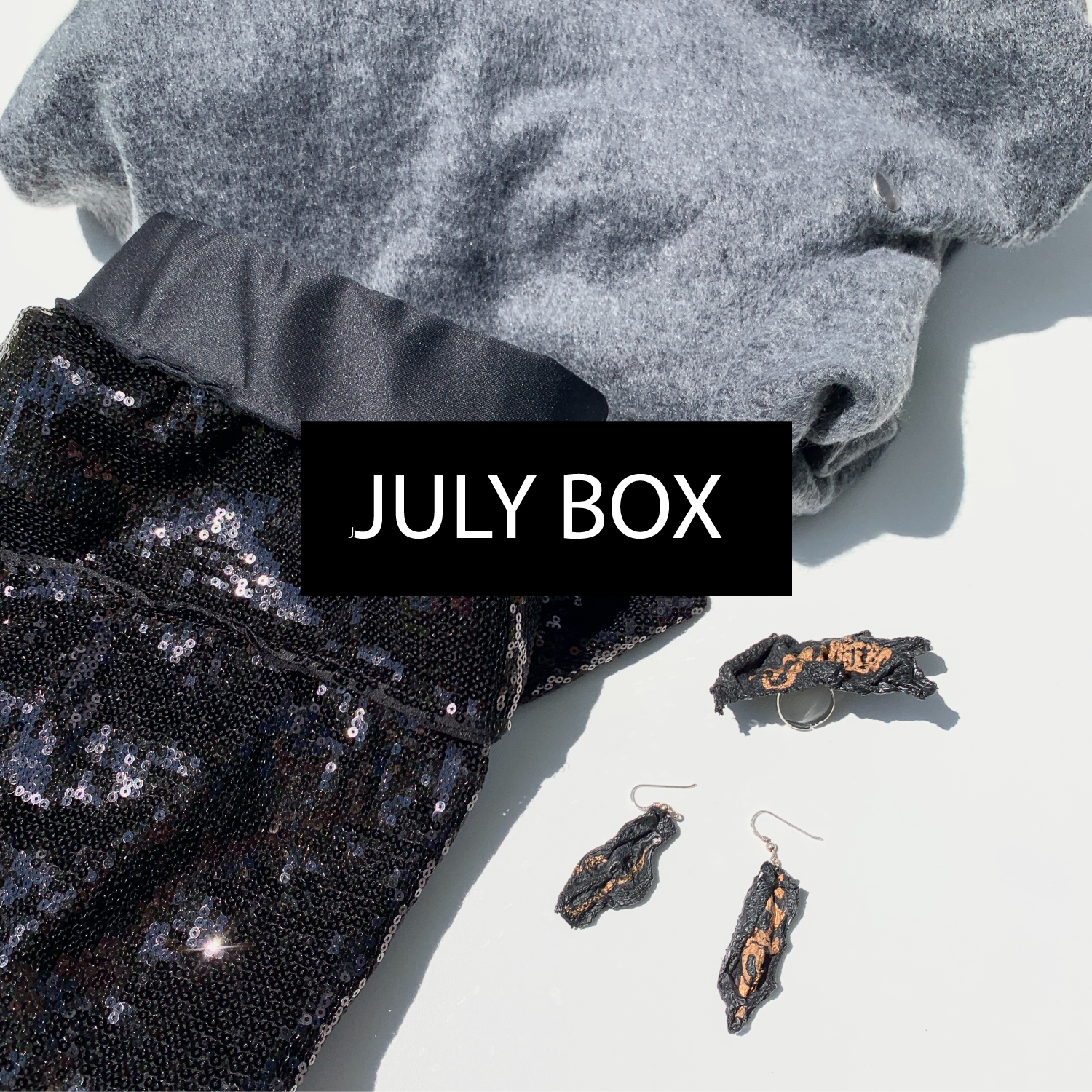 A mystery box from Malaika New York filled with sustainable clothing: a sequins skirt &amp; and grey dress by Malaika New York