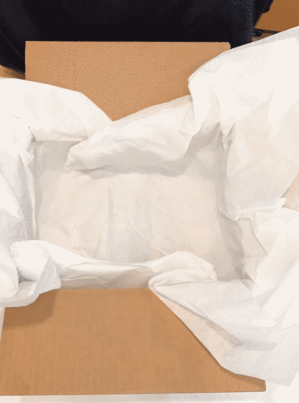 A shipping box being packed with sustainable clothing and zero waste personal care products by Malaika New York